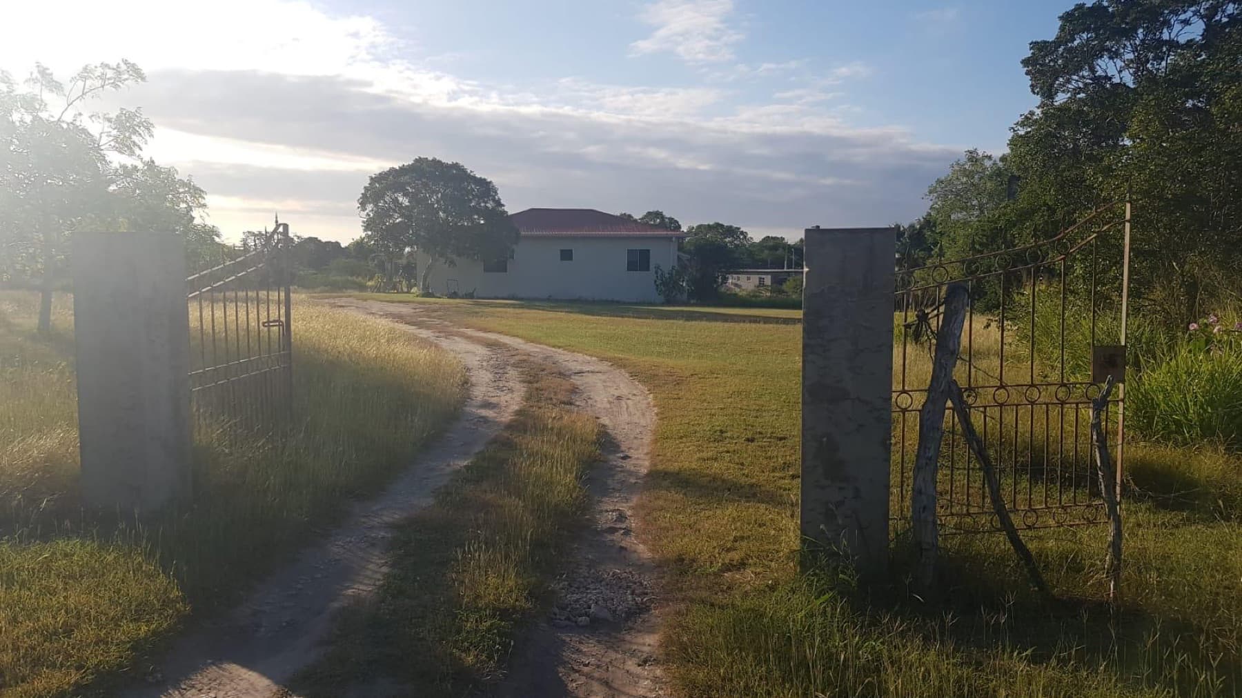 Jab's Retreat — the entrance gate and driveway leading up to the bungalow at golden hour